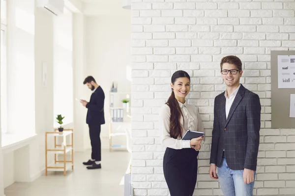 Gente de negocios de pie sonriendo mirada en una oficina blanca . — Foto de Stock