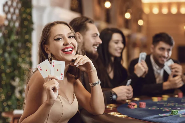 Meisje met kaarten in haar handen glimlacht bij het winnen van poker in een casino. — Stockfoto