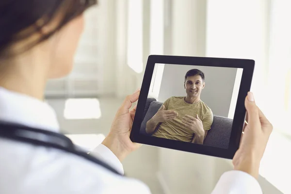 Doctor online.Man paciente en línea. Médico usando tableta videollamada habla con el paciente por el hombre con síntomas de la enfermedad prescripción . — Foto de Stock