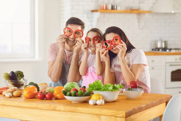 Happy family smiling at a table with fresh vegetables make salad in the kitchen. — Stock Photo, Image