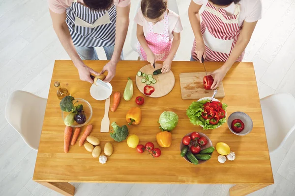 Família cozinha legumes frescos na mesa na cozinha . — Fotografia de Stock