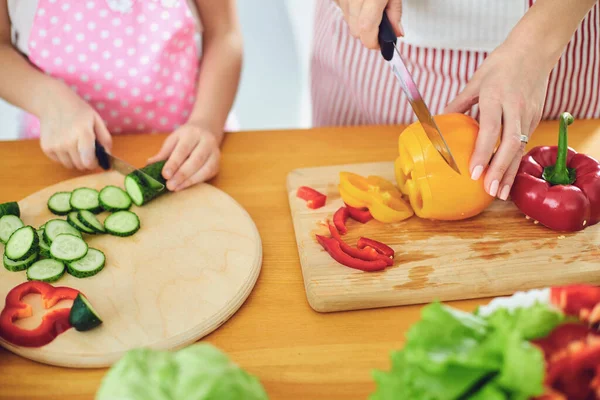 Ansiktslös. Familjehänder tillagar färsk grönsakssallad på bordet i köket. — Stockfoto