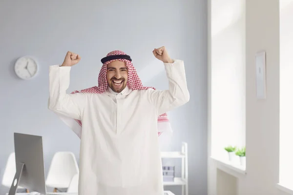 Позитивный улыбающийся арабик поднял руки в белом кабинете — стоковое фото