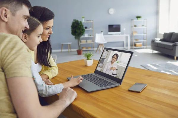 İnternette aile doktoru. Ebeveynler ve bir çocuk evdeki bilgisayarı kullanarak doktora danışıyor..