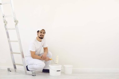 Beyaz üniformalı ev ressamı. Beyaz arka planda. Odada resim yapmak için..