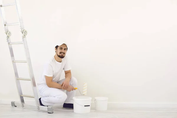 Casa pintor em uniforme branco sobre um fundo branco para pintura na sala . — Fotografia de Stock