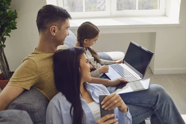 Famille heureuse utilisant ordinateur portable ensemble tout en étant assis dans la chambre . — Photo