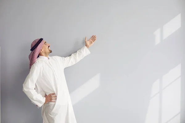 Счастливый араб в белой одежде указывает на присутствие на заднем плане — стоковое фото