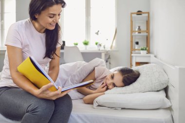 Anneler Günün kutlu olsun. Anne ve kızı evde yatakta yatarken kitap okuyorlar..