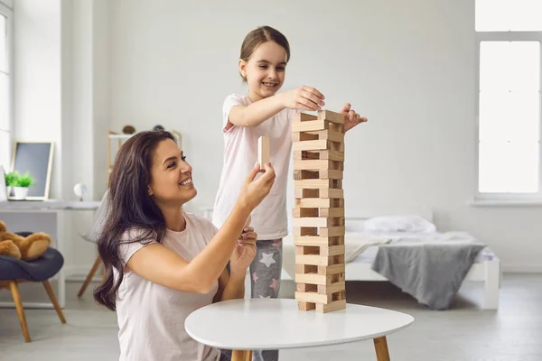 Madre e hija en pijama juegan juegos de mesa mientras están sentadas en una mesa en la sala de estar . —  Fotos de Stock