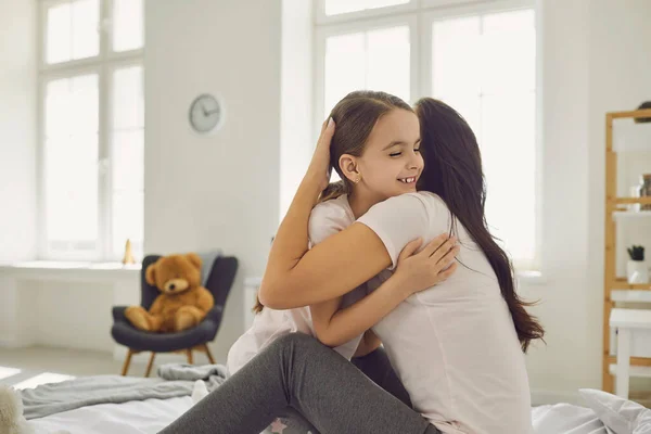 Hari ibu bahagia. Ibu dan anak memeluk tersenyum sambil duduk di tempat tidur di kamar — Stok Foto