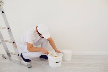 Beyaz üniformalı ev ressamı. Beyaz arka planda. Odada resim yapmak için..