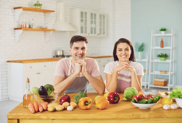 Happy middle couple smiling at a table with fresh vegetables make salad in the kitchen. — Stock Photo, Image