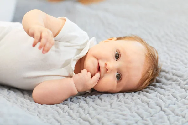 Bebê atraente sorrindo deitado na cama — Fotografia de Stock