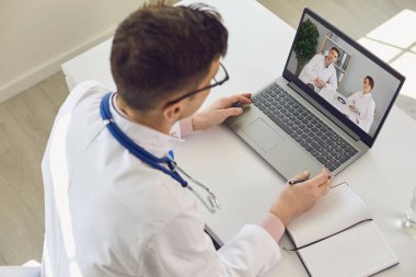 Bir grup doktor klinikte oturan doktorlara video konferansı düzenliyor..