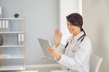Doktor hatta. Tablet video kullanan kadın doktor, iş kadınının uzaktan hastasıyla konuşuyor..