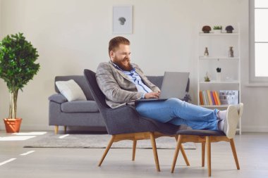 Merkez büroda çalışıyorum. Komik şişman adam dairede dizüstü bilgisayar kullanıyor..