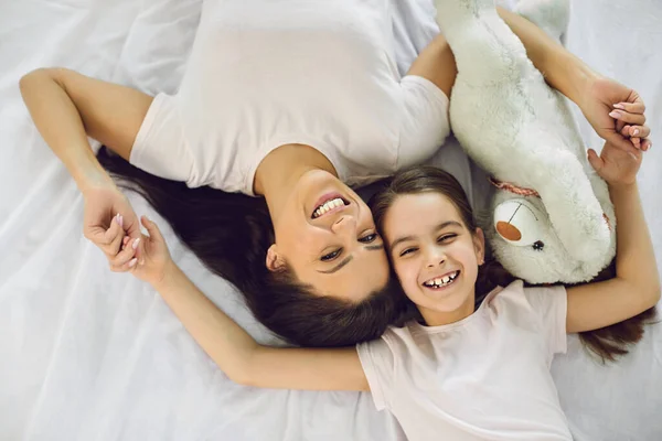 Happy mothers day. Top view.Portrait of happy mother and daughter lying on the bed at home. — Stock Photo, Image