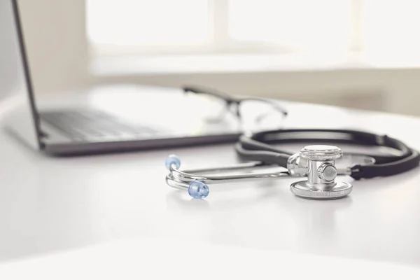 Concepto de llamada médica en línea. Telemedicina. Estetoscopio y portátil en una mesa blanca . — Foto de Stock