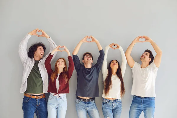 Група друзів, які роблять знак серця руками на сірому фоні . — стокове фото