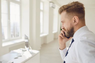 Kendine güvenen bir iş adamı ofiste telefon görüşmesi yapıyor.
