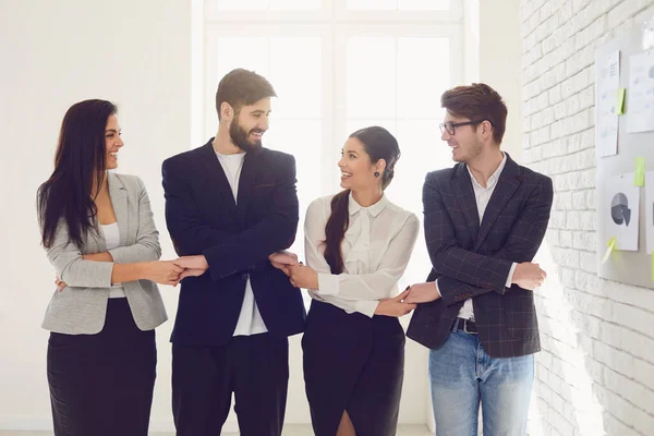 Equipo creativo de gente de negocios tomados de la mano mientras están de pie en interiores . —  Fotos de Stock