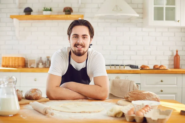 面包店厨房里的新鲜面包背景下，贝克大胡子男人笑了 — 图库照片