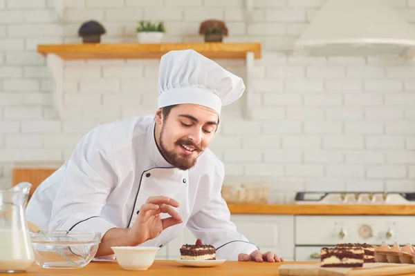 Um chef de pastelaria masculino trabalha decorando um bolo em uma padaria de cozinha — Fotografia de Stock