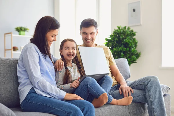 Gelukkige familie laptop online. Ouders en een kind meisje glimlachen op een laptop op hun gemak in een weekend thuis. — Stockfoto