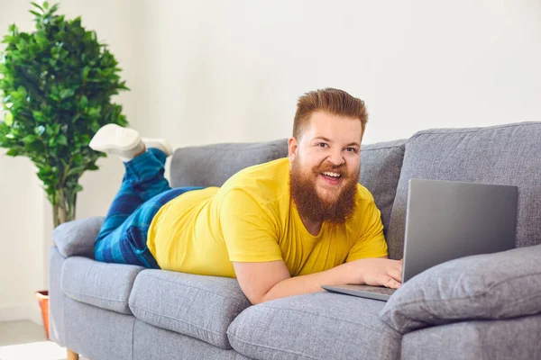 Engraçado homem gordo trabalhando compras on-line shrpping assistindo a um vídeo em casa na sala . — Fotografia de Stock