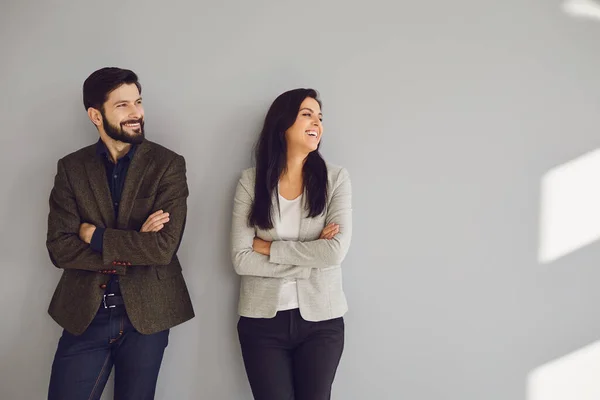 Un hombre de negocios y una mujer de negocios están de pie contra una pared gris — Foto de Stock