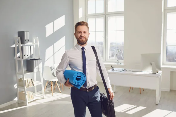 Glücklicher erfolgreicher Geschäftsmann im weißen Hemd mit Yogamatte im Büro. — Stockfoto