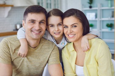 Mutlu gülümseyen neşeli aile oturma odasında birbirine sarılıyor..