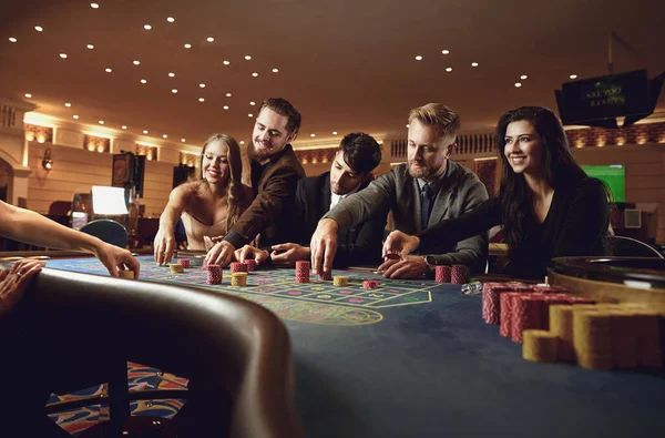 Mensen gokken 's nachts aan de roulette tafel in een casino. — Stockfoto