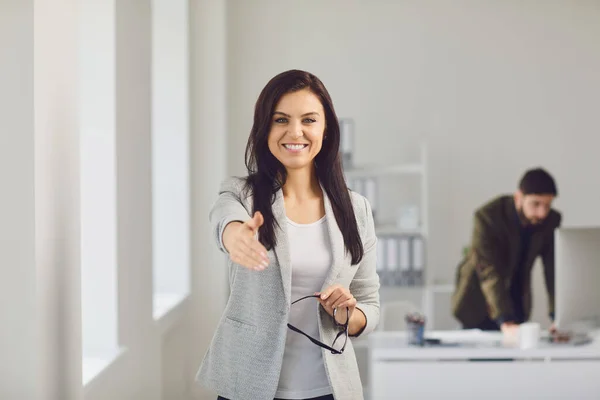 El sıkışma teklifi. Bir iş kadını ofiste dururken el sıkışmayı teklif eder.. — Stok fotoğraf