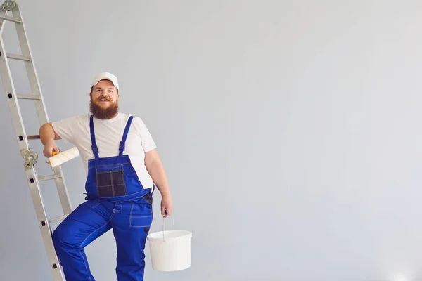 Pintura de pintor. Engraçado pintor masculino com um patinador de patins de pé pinturas no fundo . — Fotografia de Stock