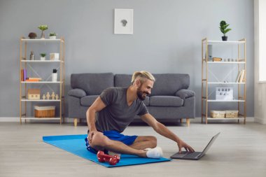 Spor egzersiz fitness çevrimiçi video çağrısı. Evdeki bir laptopta online fitness kursu alıştırması yapan bir adam..