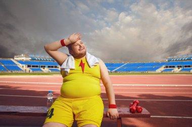 Thick funny man resting after a workout at the stadium. clipart