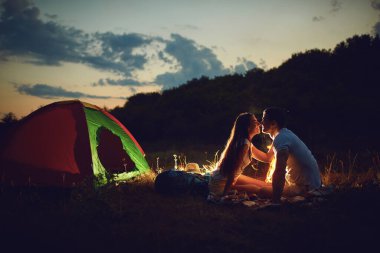 A young couple is cooking bread on a fire at night