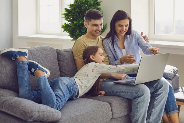 Familjens bärbara dator online. Föräldrar och ett barn tittar på en bärbar dator på sin fritid i en helg hemma. — Stockfoto