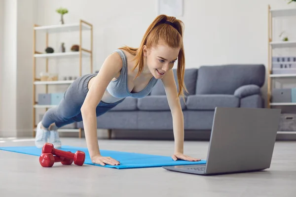 온라인 스포츠 홈 경기. 가정 에서의 직장. 빨간 머리 여자 가 집에서 운동하는 모습. — 스톡 사진