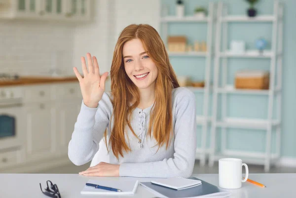 Mädchen mit Blick auf Laptop-Kamera Online-Video-Web-Chat-Anruf begrüßt mit der Hand lächelnd, während zu Hause sitzen. — Stockfoto