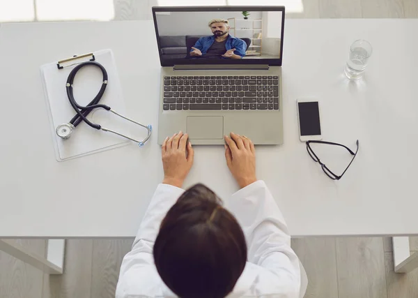 Dottore online. Il dottore parla con un paziente usando un portatile seduto dietro una cannuccia in un ufficio della clinica. Consulenza medica online . — Foto Stock