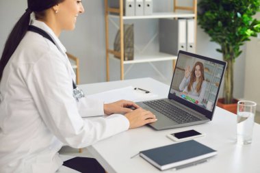 Doktor hatta. Laptop görüntülü konuşma yapan kadın doktor, iş kadınlarının hastalarıyla uzaktan konuşuyor..