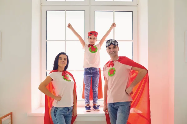 Süper kahramanların ailesi. Mutlu anne baba ve küçük kız odada gülüyorlar. — Stok fotoğraf