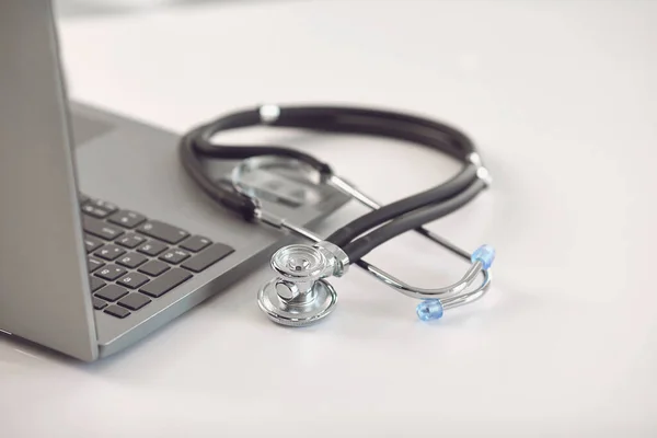 Internetowy lekarz dzwoni koncepcja. Telemedycyna. Stetoskop i laptop na białym stole. — Zdjęcie stockowe