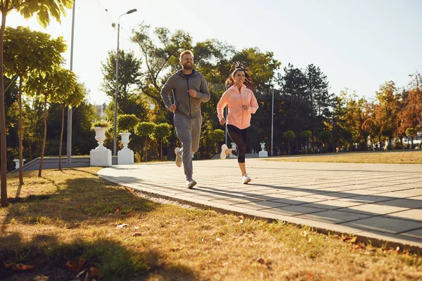 Sportliches Paar läuft morgens die Stadtstraße entlang. — Stockfoto