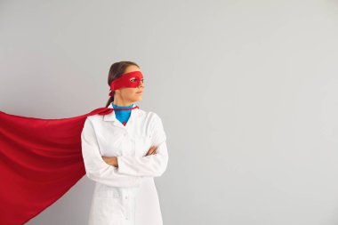 Gri arka planda kendine güvenen kadın süper kahraman doktor..