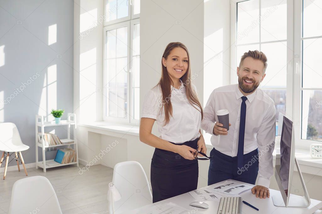 Positive businessman and businesswoman smiling in a white office.