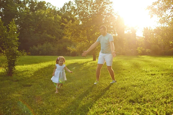 Fathers day. Father plays with his daughter in the summer park. — Stok fotoğraf